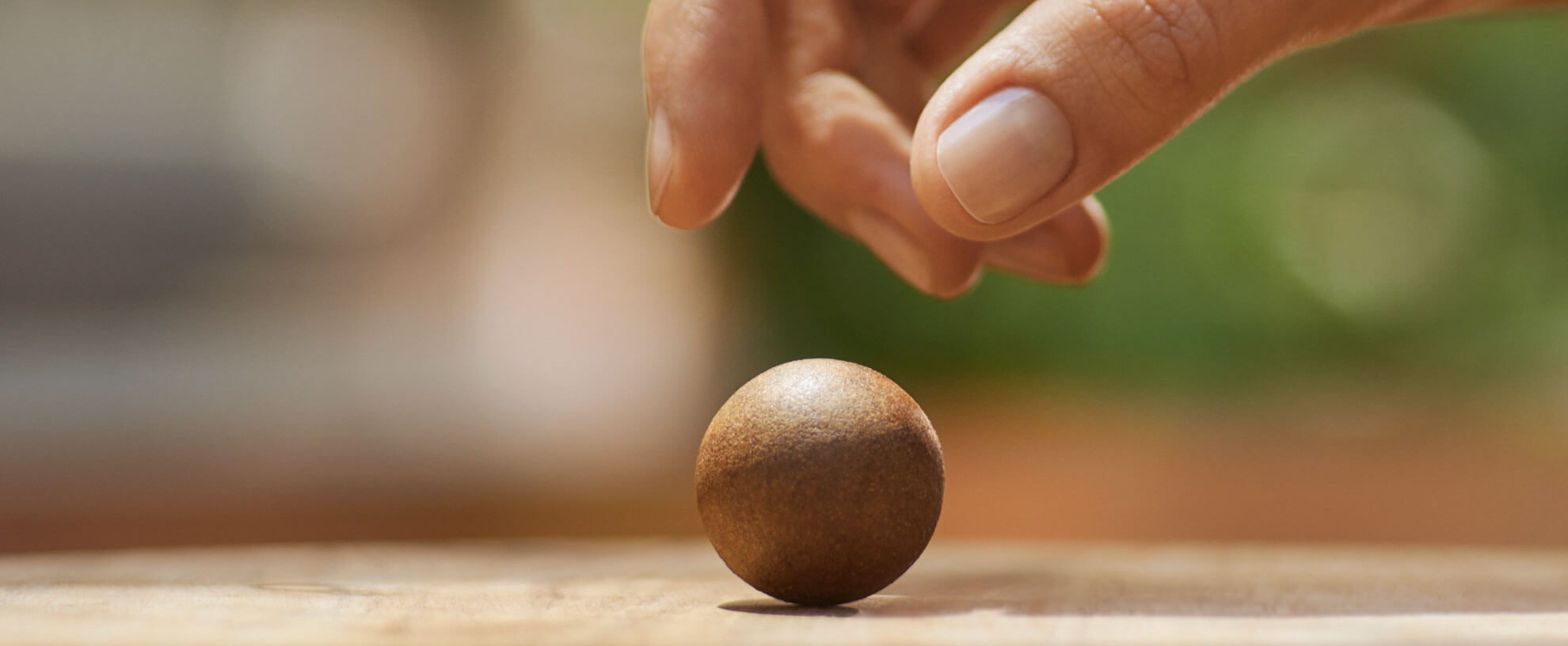 Eine Hand greift nach einem Coffee Ball, der auf einem Tisch liegt.