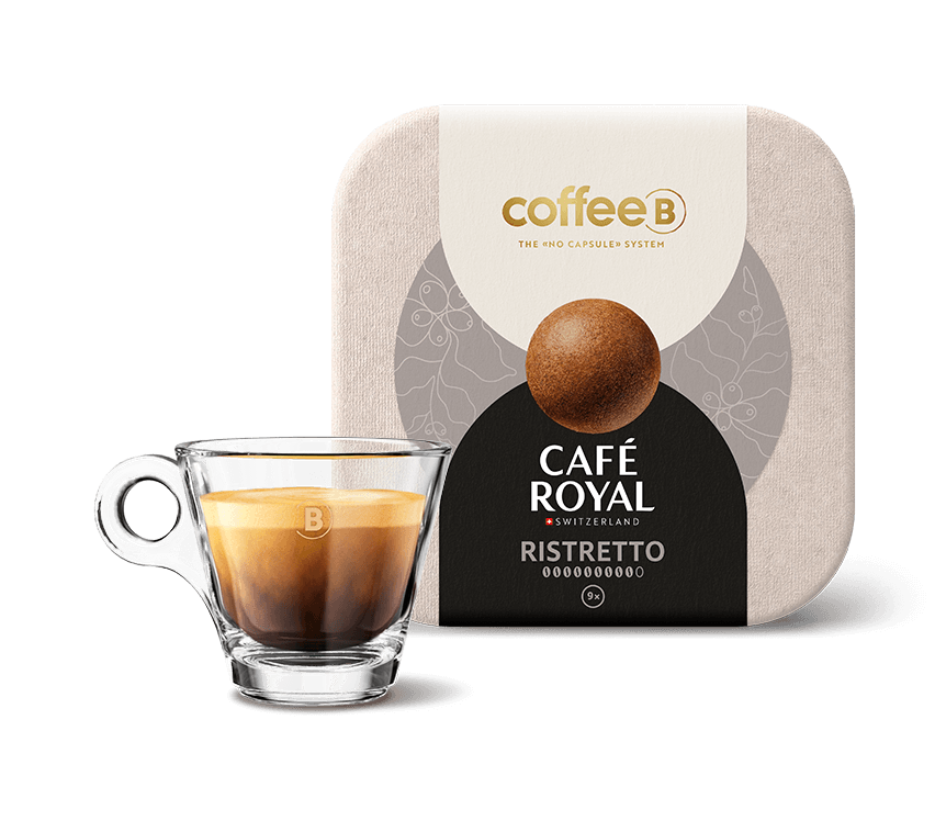 Neun Coffee Balls Ristretto von CoffeeB mit einer gefüllten CoffeeB Espresso-Tasse.