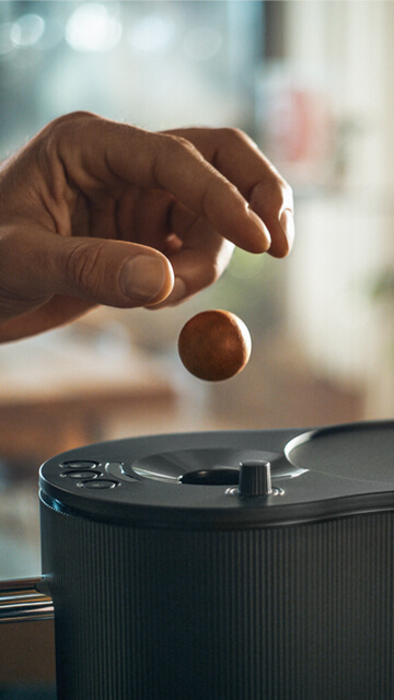 Ein Coffee Ball wird in eine CoffeeB Kaffeemaschine eingeworfen.