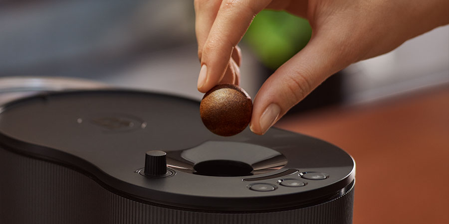 Ein Coffee Ball wird in eine CoffeeB Kaffeemaschine eingeworfen.